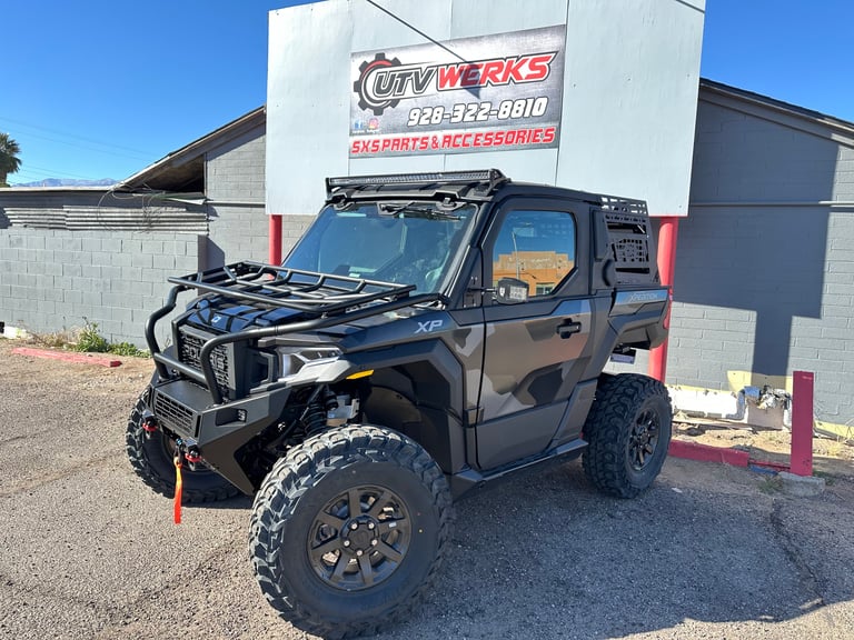 Black lifted utility vehicle on display at a dealership with CURV WERKS sign in background