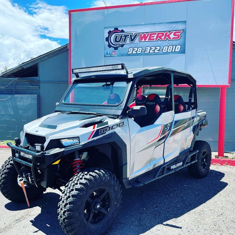 Modified white UTV with red accents parked in front of City Werks shop with blue building and signage