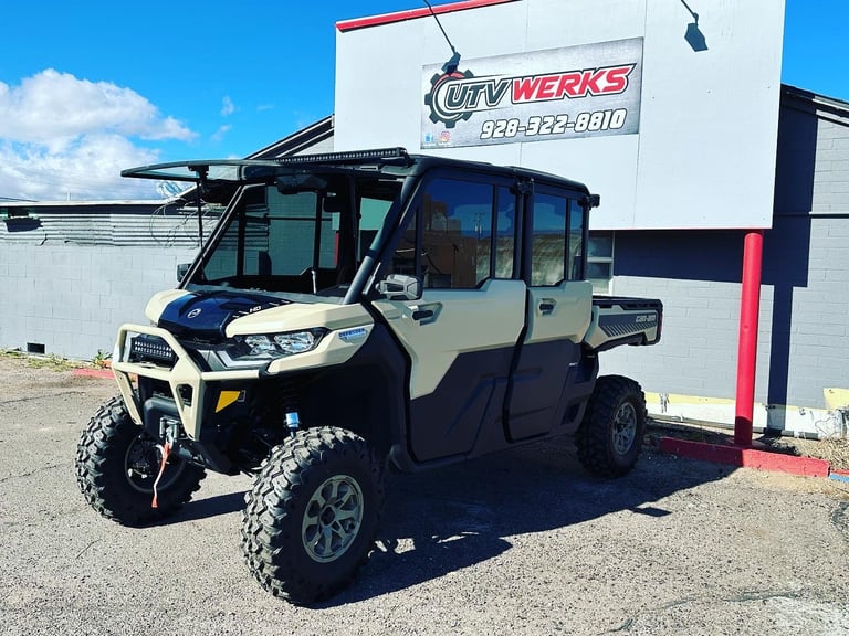 Four-seater UTV with cream and black exterior parked outside UTV Werks shop with clear blue sky