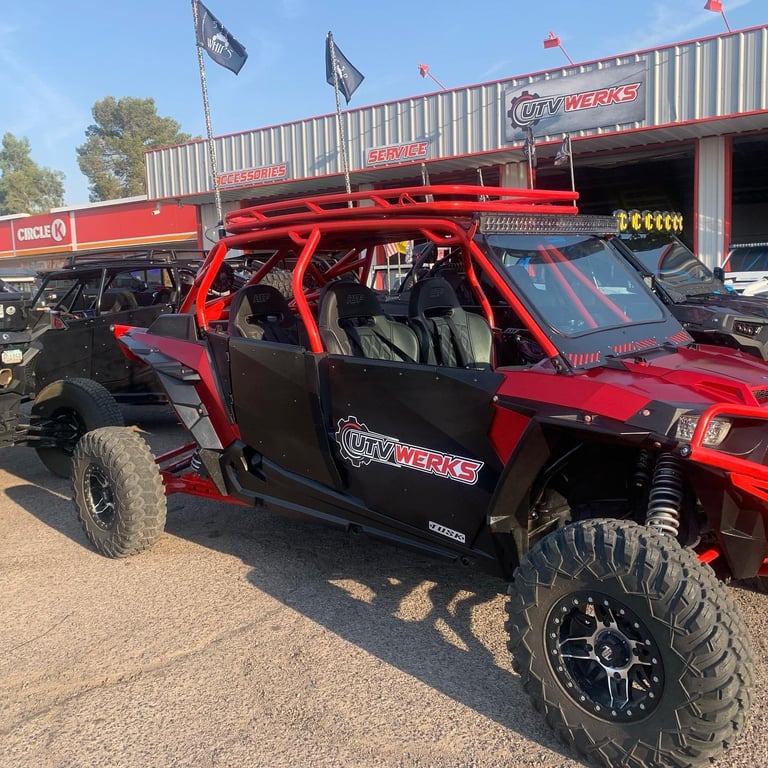 Red and black UTV with bright red roll cage and large tires at an off-road vehicle dealership