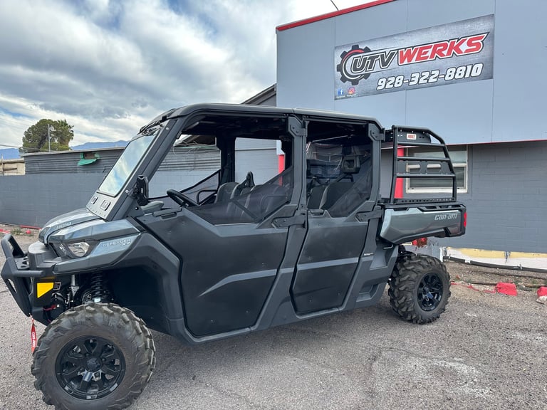 Black side-by-side UTV with doors open displayed at dealership parking lot