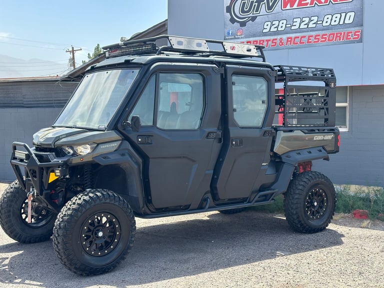 Black UTV with roof rack and rear cargo carrier parked at outdoor dealership lot