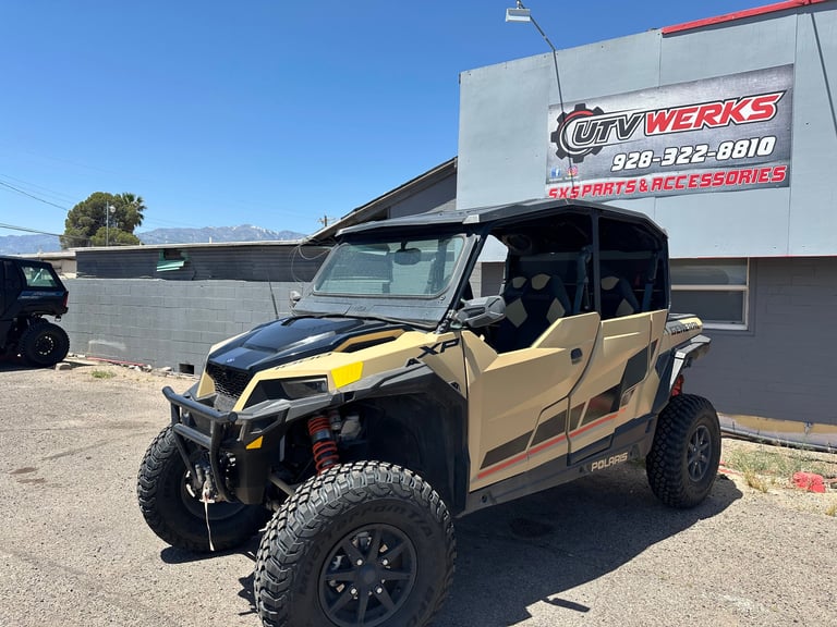 Tan and black lifted UTV with yellow accents parked outside ATV Werks shop building