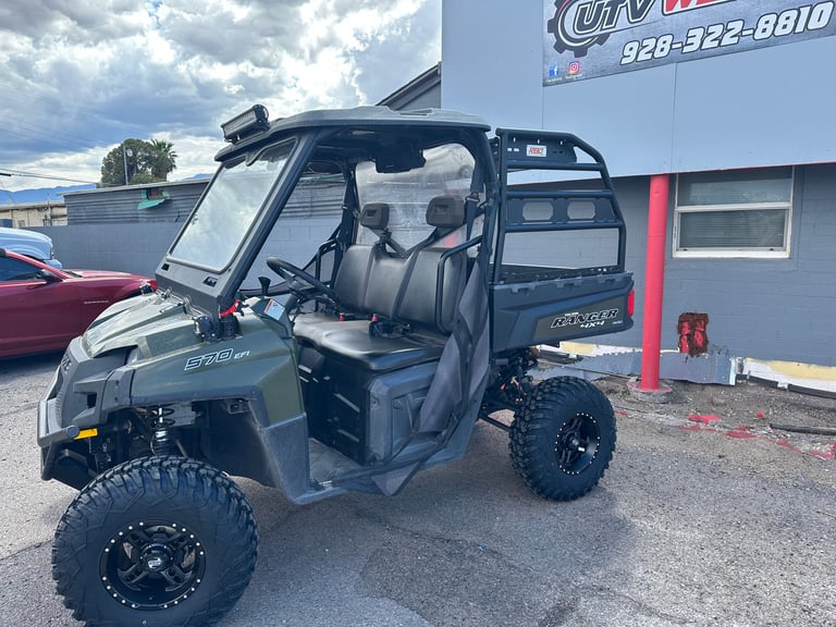 Black UTV with open doors and lifted suspension on display in dealership lot
