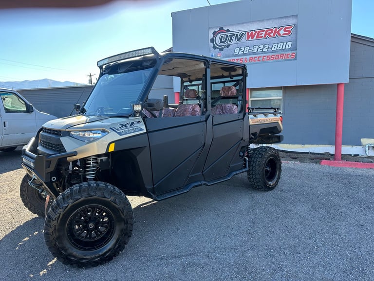 Black lifted UTV with doors parked in front of City Werks shop building with mountain backdrop