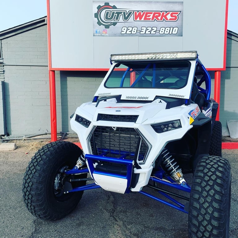 Custom white and blue UTV with oversized tires and lifted suspension parked in front of City Werks shop