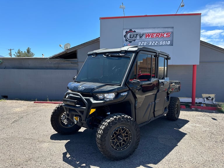 Black enclosed side-by-side ATV parked outside ATV Werks shop with large alloy wheels visible in daylight